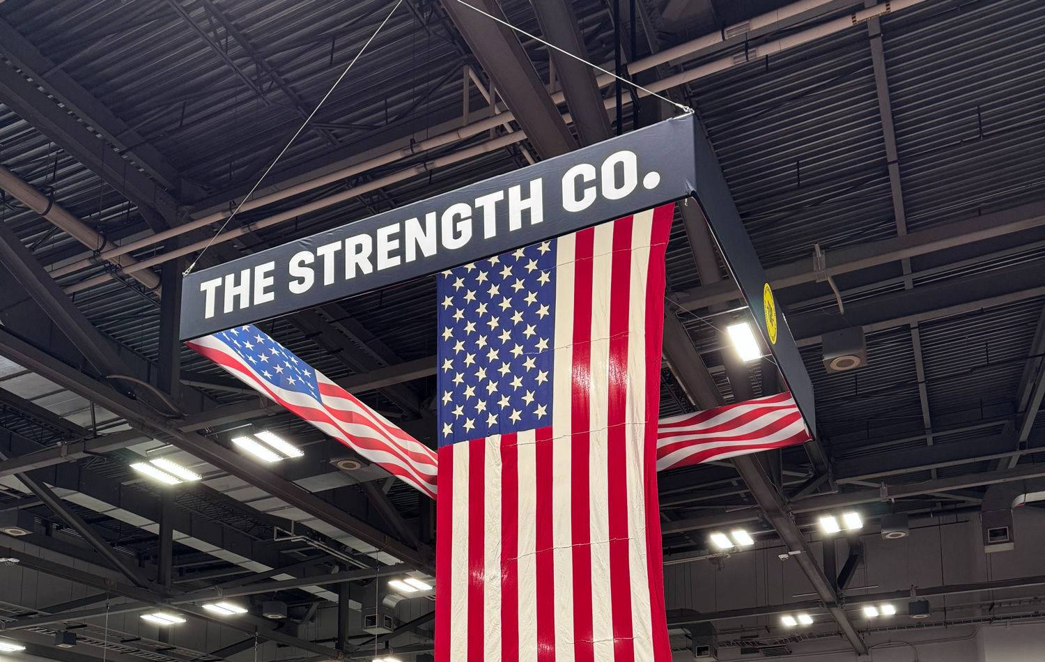The Strength Co. sign and American flag hanging over the competition floor